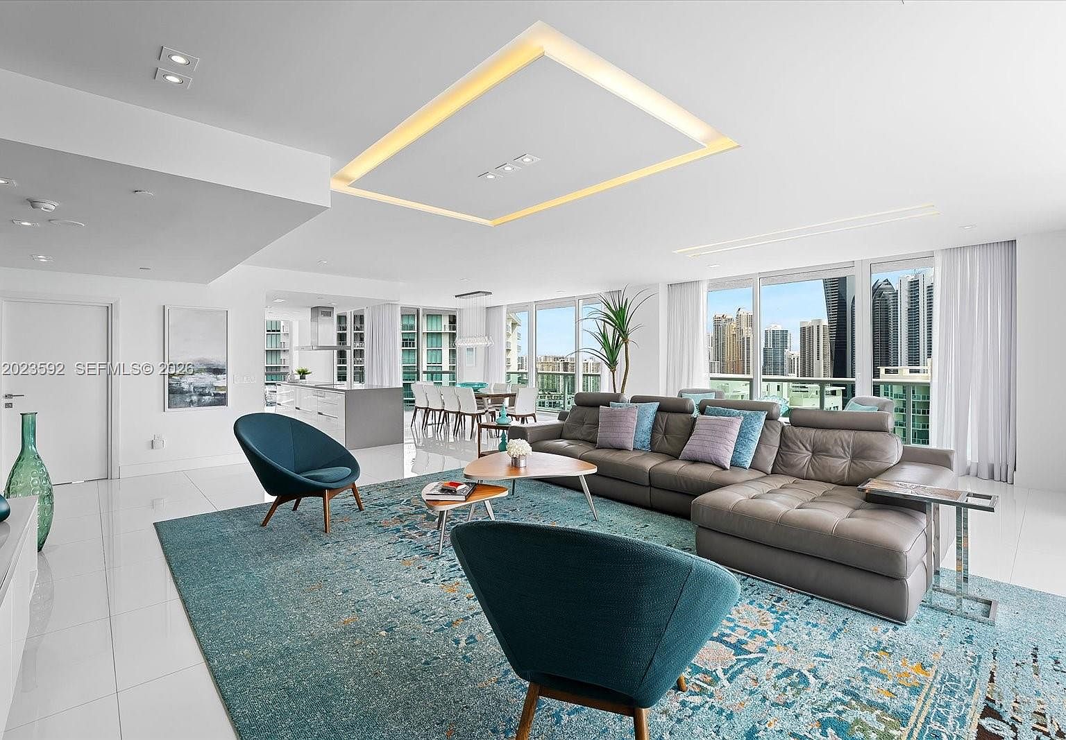 Living and dining area with custom recessed ceiling lighting and the kitchen line visible in the background