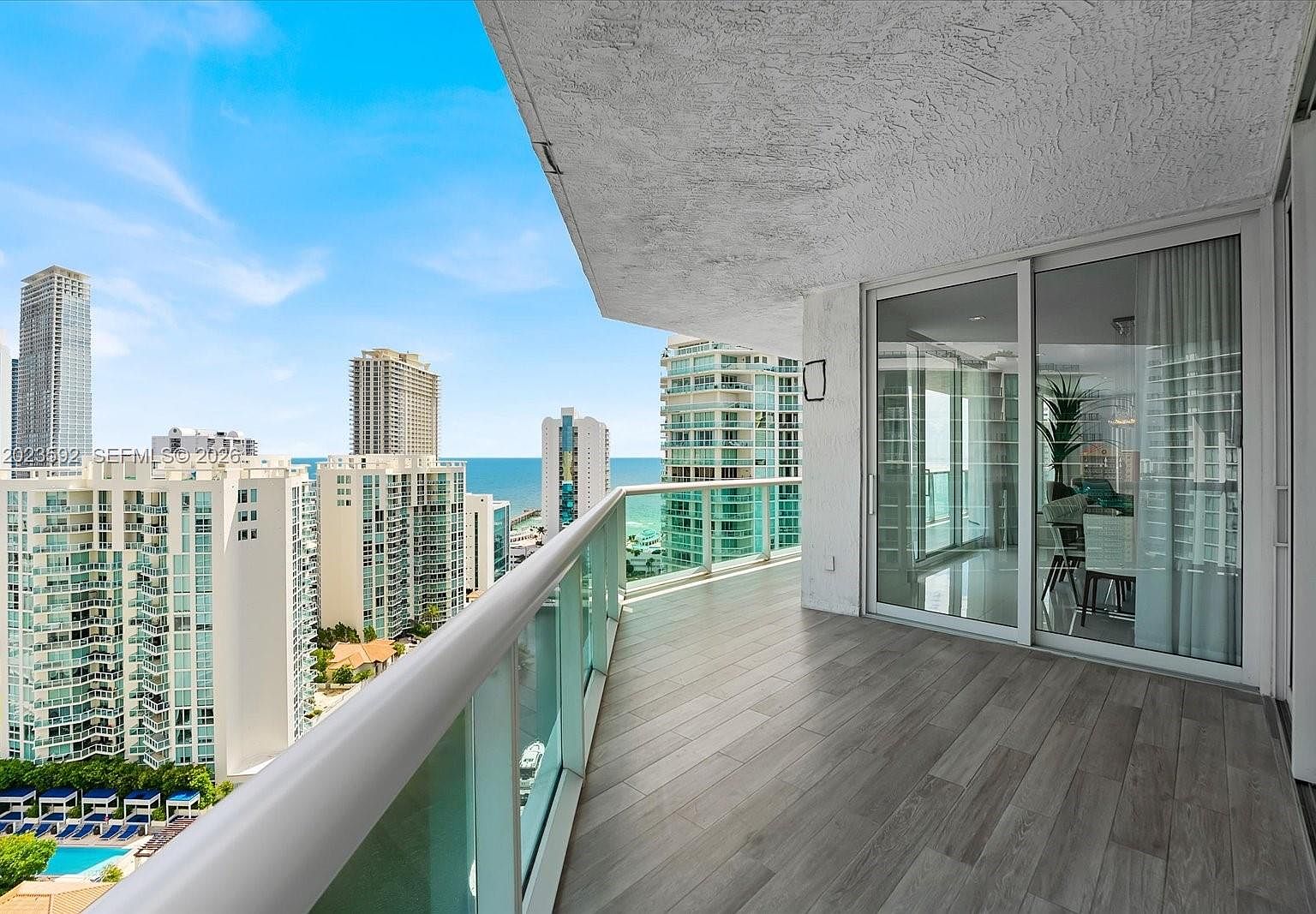 The wrap-around balcony floor with porcelain plank tile leading toward the corner where the ocean meets the bay