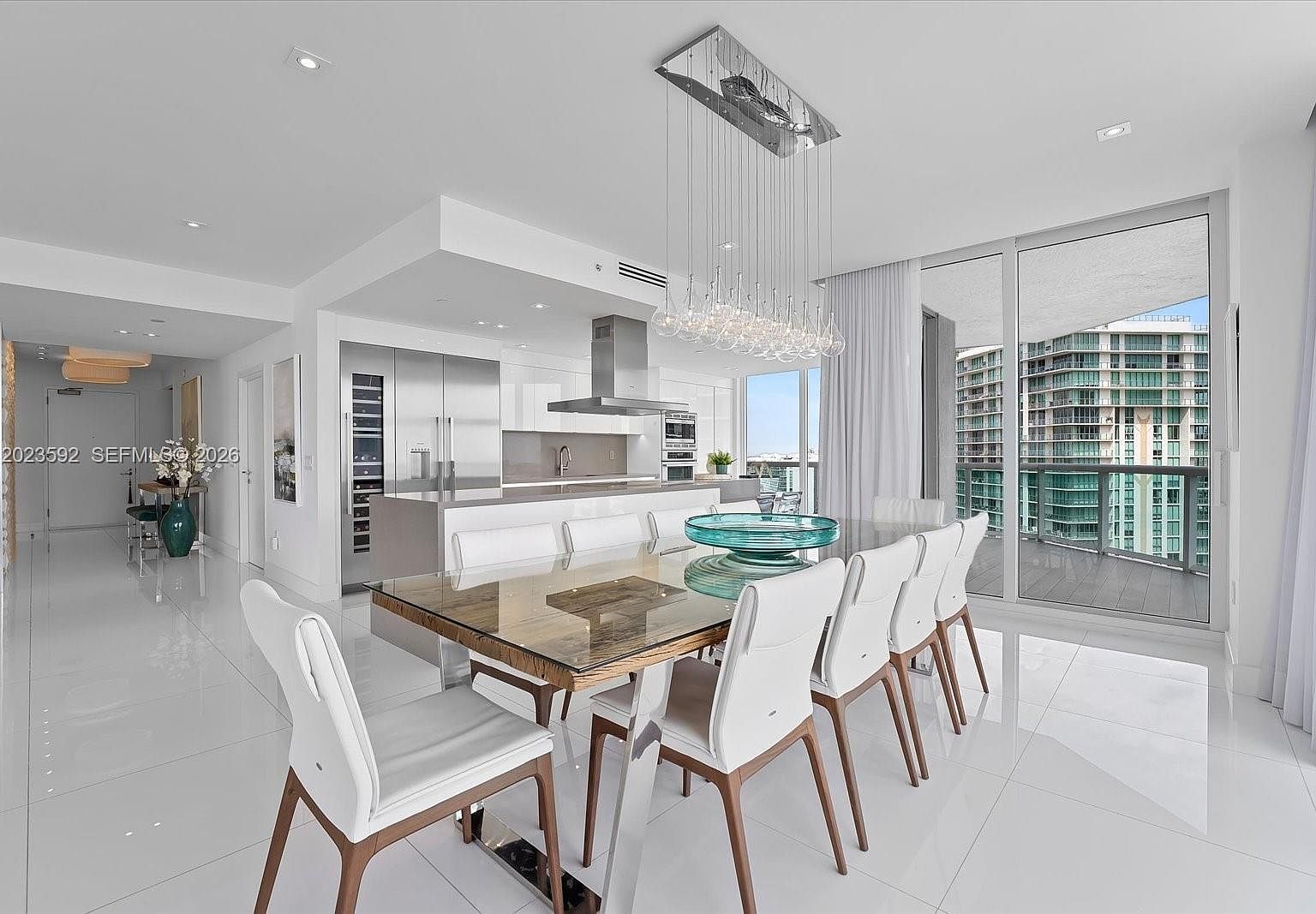 Dining table with sculptural pendant lighting framed by sliding glass to the intracoastal side