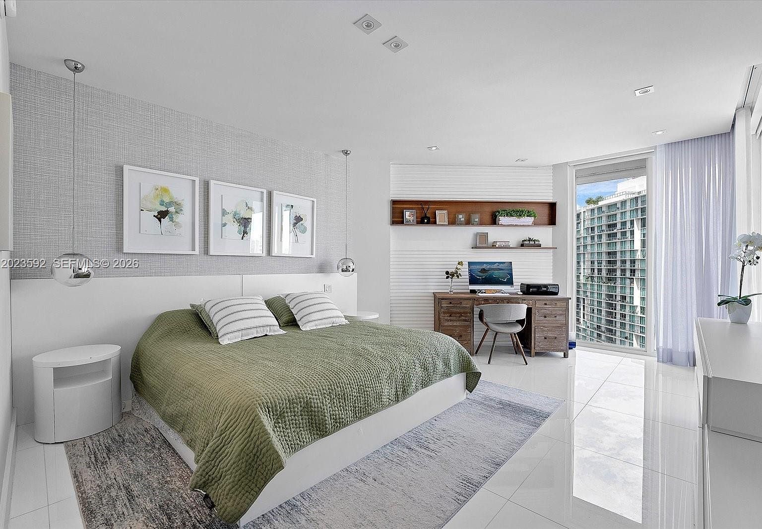 Primary bedroom suite with a low platform bed, draped sheer linen, and direct access to the balcony